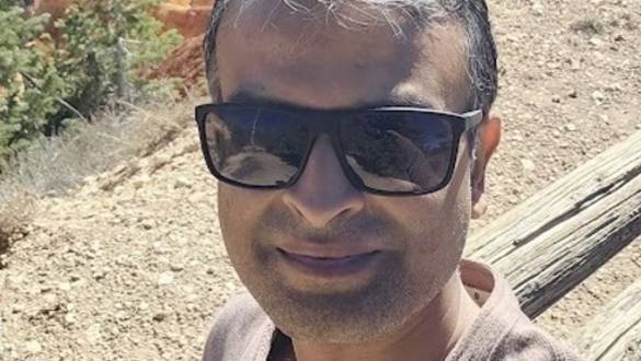 Man wearing sunglasses taking a selfie at a red rock canyon landscape, likely Bryce Canyon.
