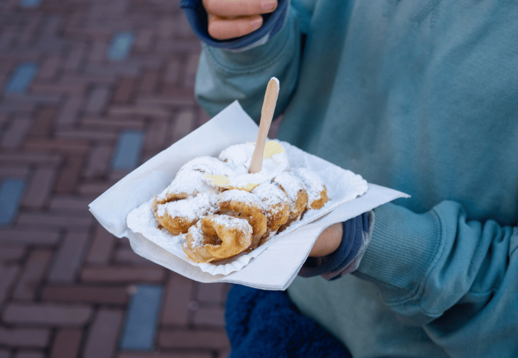 Tourist enjoying traditional dutch poffertjes with powdered sugar and butter