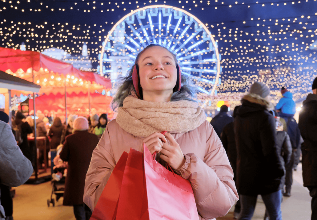 Happy teen girl with red shopping bags at Christmas market