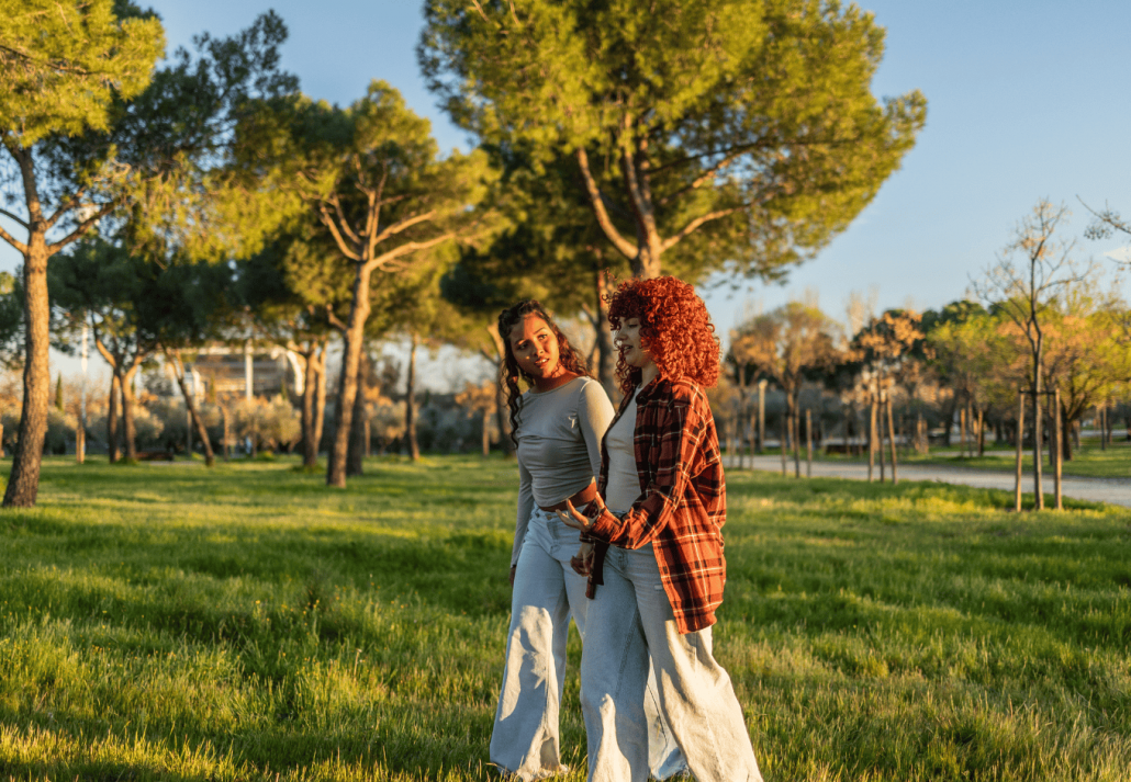 Two young women walking and talking in a park at sunset