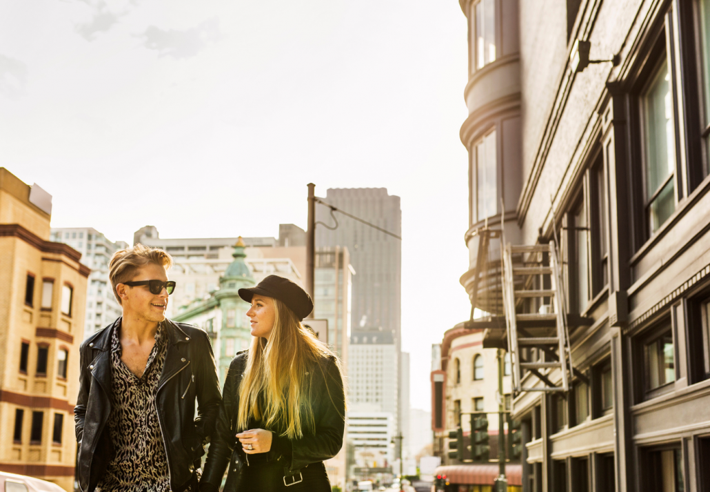 Young man and woman walking in city and talking
