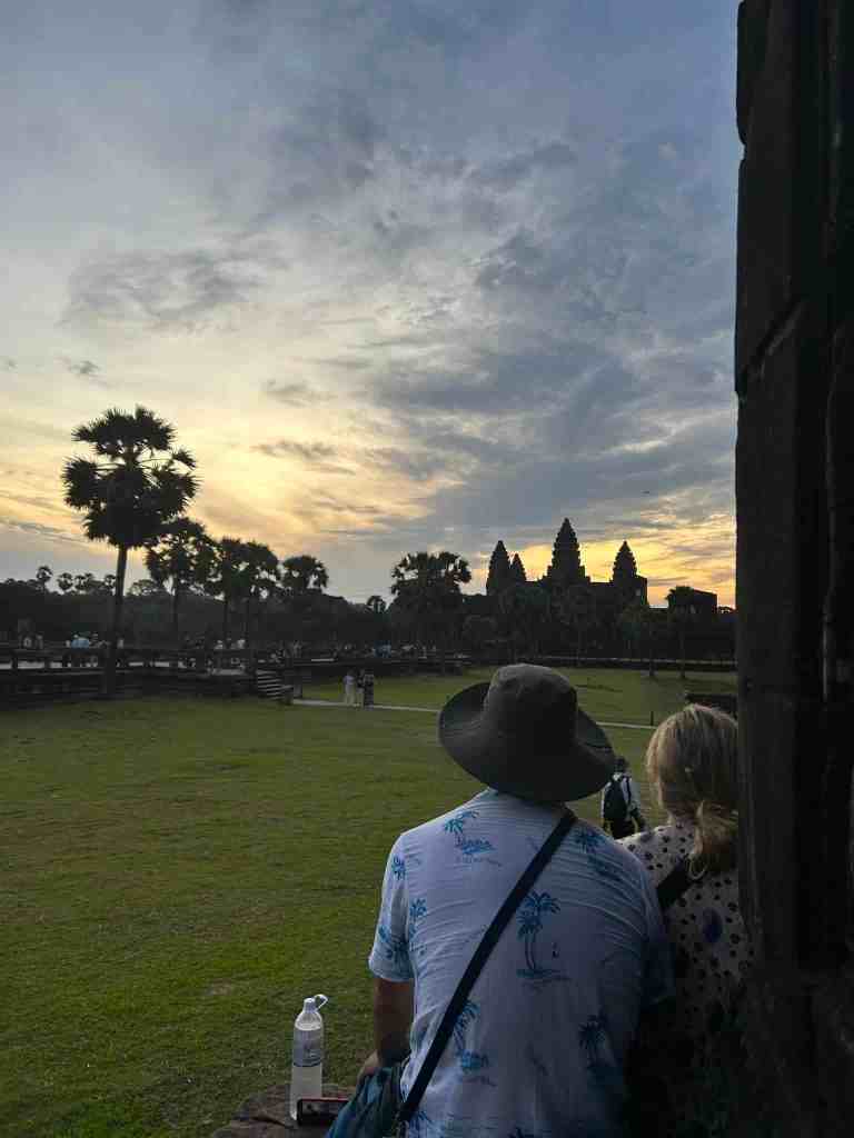 watching the sun rise over Angkor Wat two people sitting anw watching