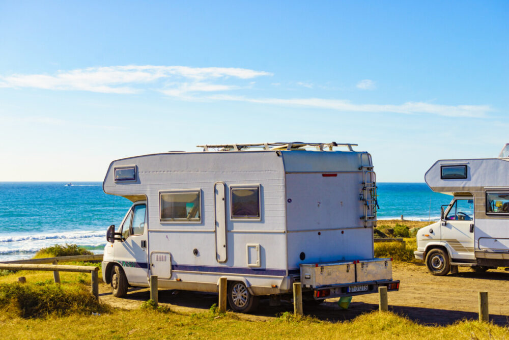Camper cars rv camping on beach sea shore, sunny summer day. Spain Murcia region, Calblanque Regional Park.